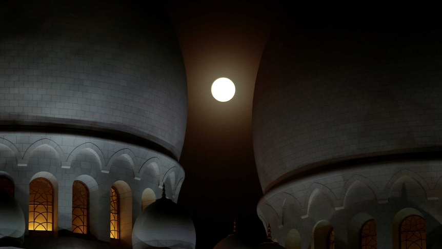 A lunar eclipse of a full "Blood Moon" rises behind the Sheikh Zayed Grand Mosque in Abu Dhabi.