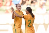 Sam Kerr and Catlin Foord hold hands up to each other in celebrating a goal.