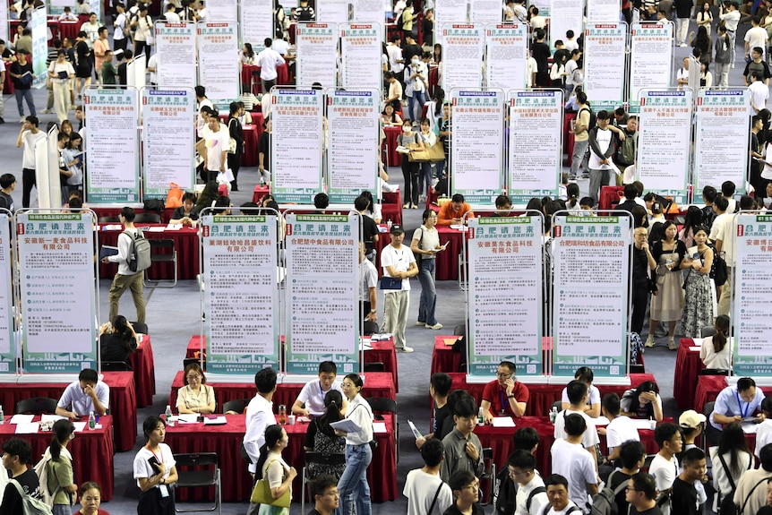 People attend a job fair for university graduates at a gymnasium.