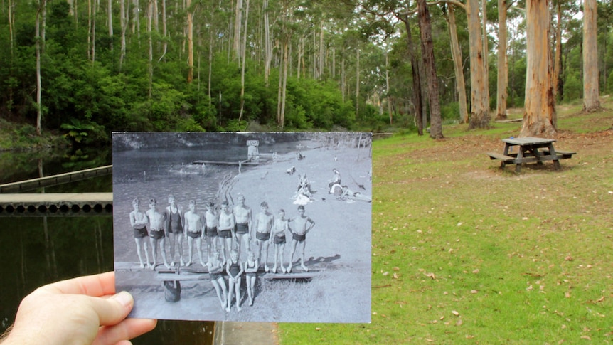 A hand holds a black and white picture of children with a park in the background.