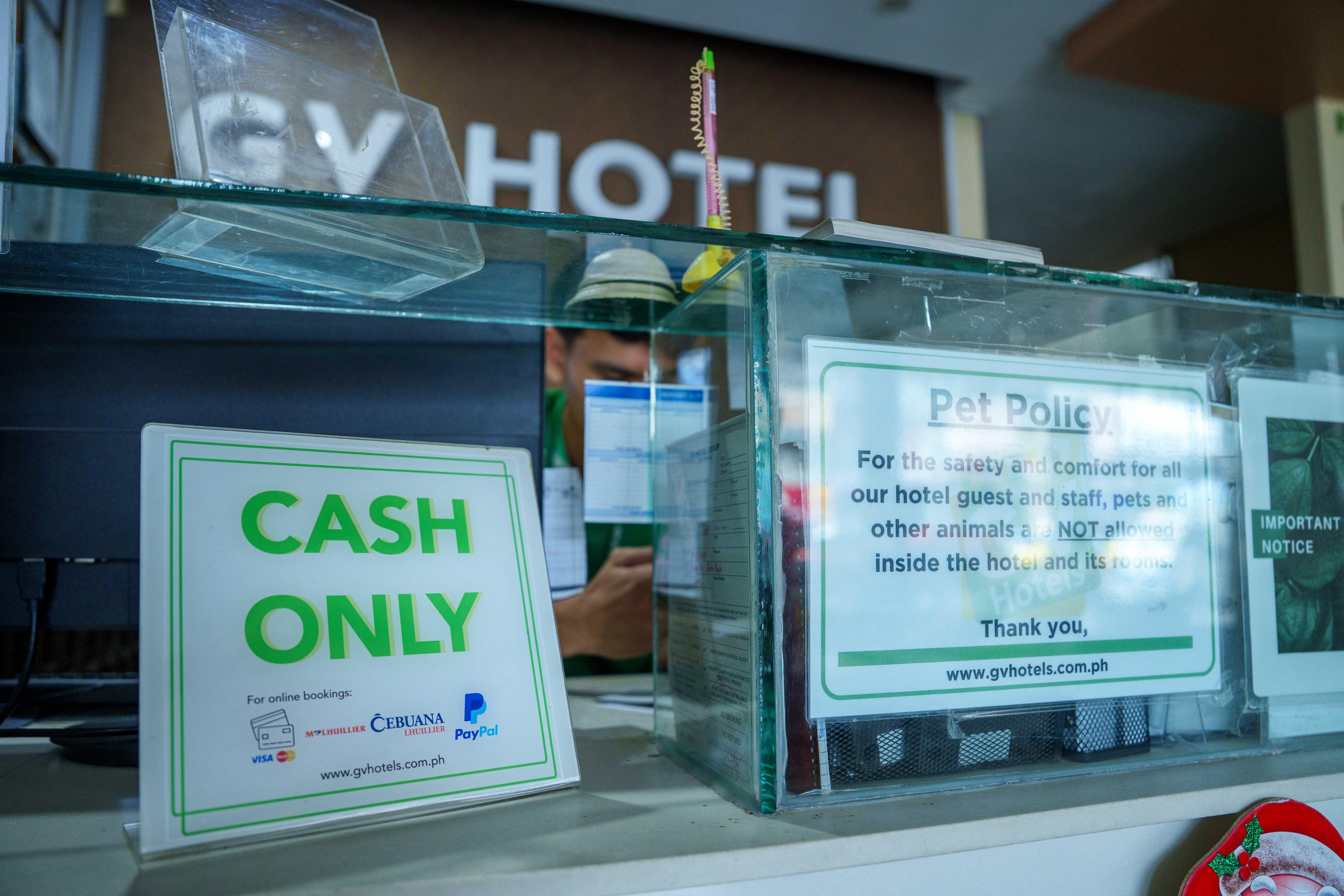Coladas em uma vitrine em frente à recepção de um hotel estão placas que dizem SOMENTE DINHEIRO e POLÍTICA DE ANIMAIS DE ESTIMAÇÃO.