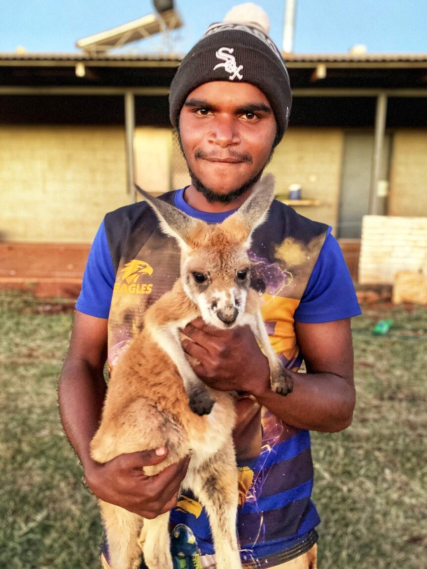 A young man holds a kangaroo.