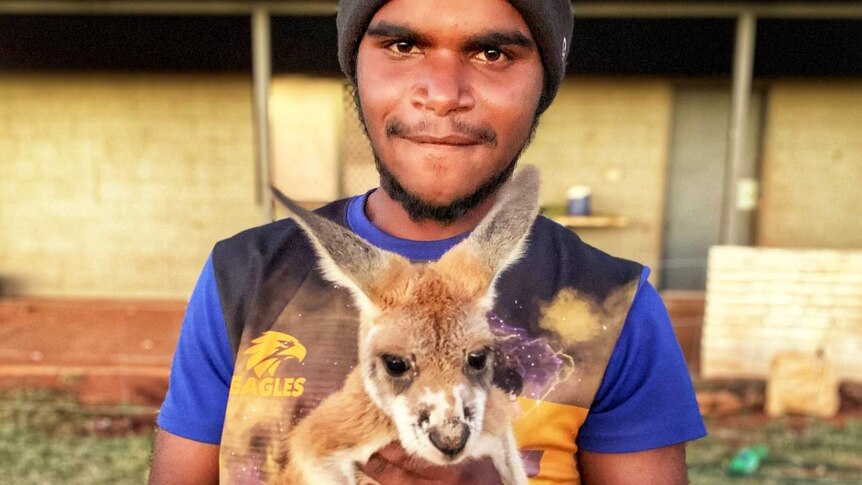 A young man holds a kangaroo.