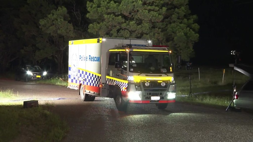 A police truck driving along a road at night in Bungonia