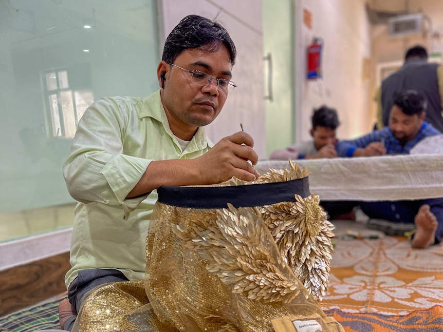 A man working on a gold garment