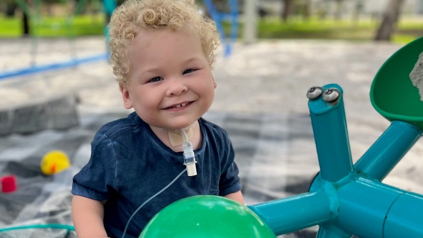 A picture of Arlo smiling at a playground and holding a balloon 