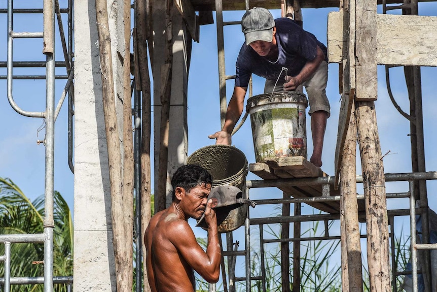 A tradie wipes his face with his cap in the burning heat.