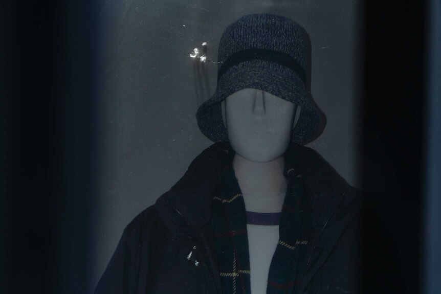 A mannequin in a knitted hat, jacket and tartan scarf