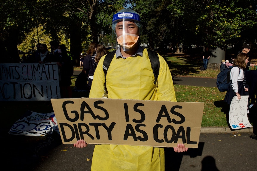 A protester at a climate change rally in Melbourne wears full PPE and holds an anti-gas sign.