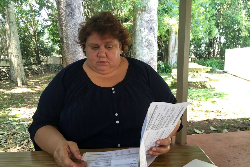 A woman reading through documents on a desk outside.