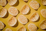 A top-down photograph of a number of individual potato chips laid out on a table