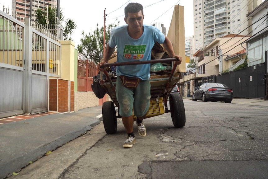 A catadore pulls his cart along a street.