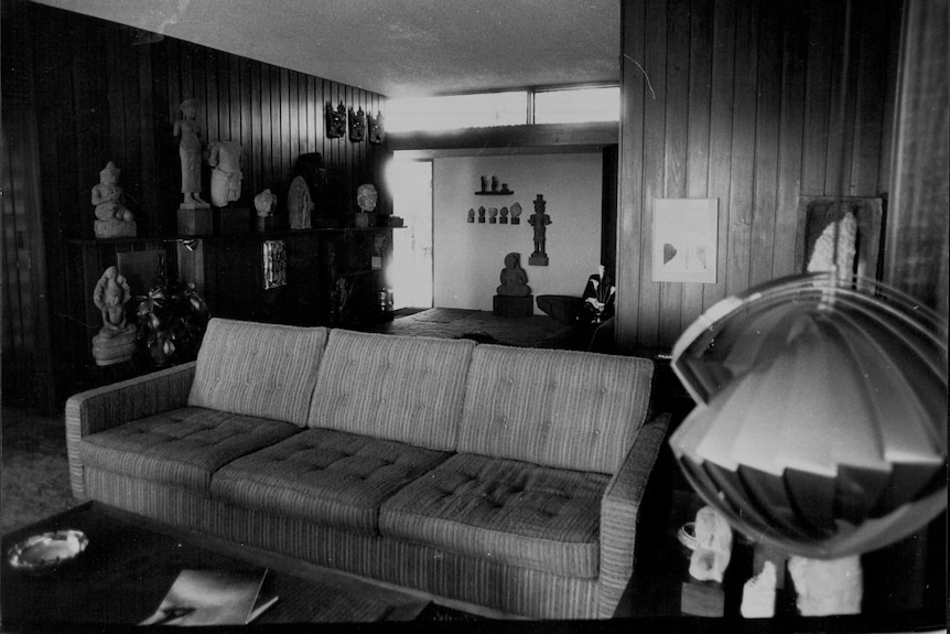 A living room with wood panelled walls covered in sculptures