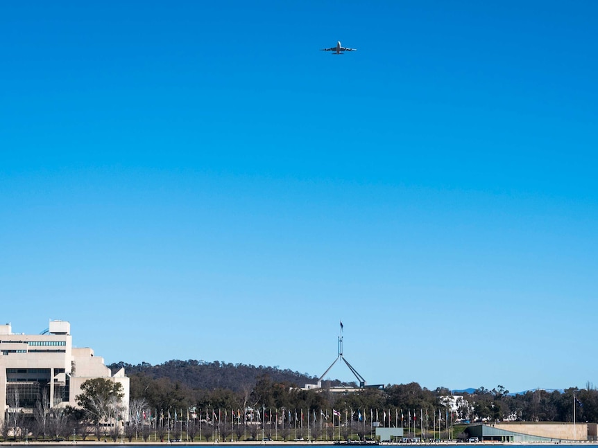 A Qantas Boeing 747 flying over Parliament House in Canberra.