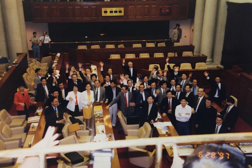 An aerial shot shows members of the HK legislative council, martin lee stands on the front left hand side wearing glasses