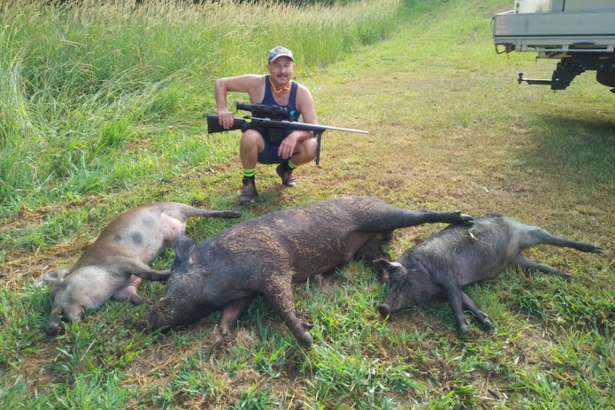 David Hard crouches behind three of the pigs he has shot.