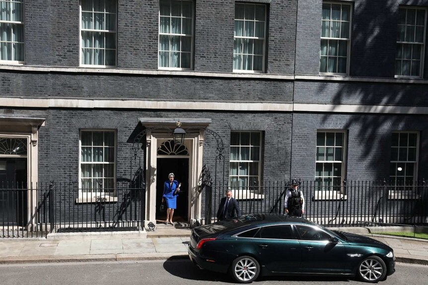 A wide shot shows the dark Georgian facade of 10 Downing Street in London with a green Jaguar parked out the front.