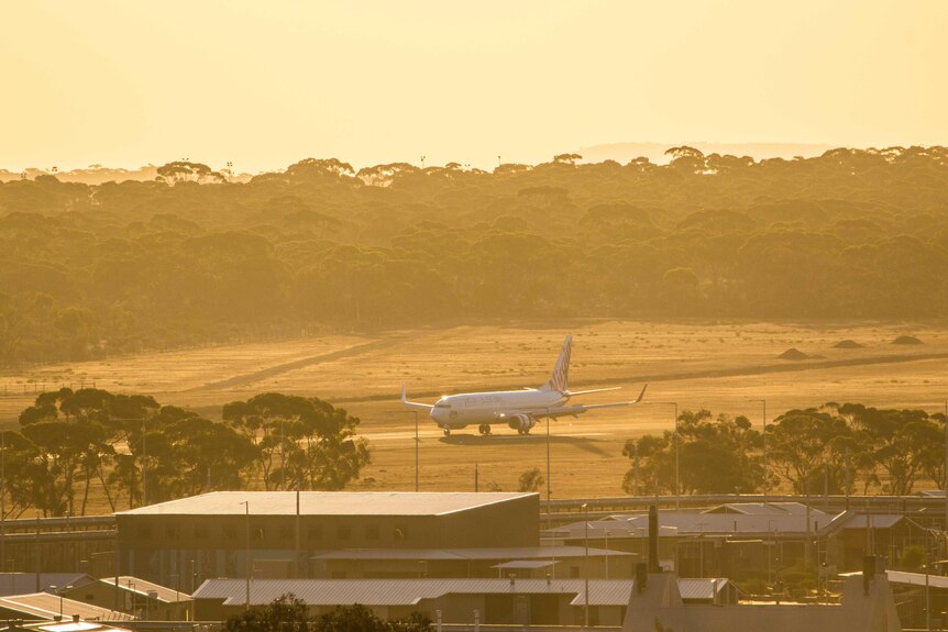 A jet passenger aircraft taxis on a runway at sunset.   