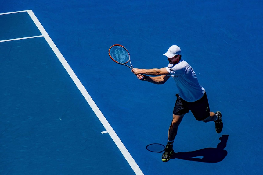 A man hits a backhand shot on the tennis court