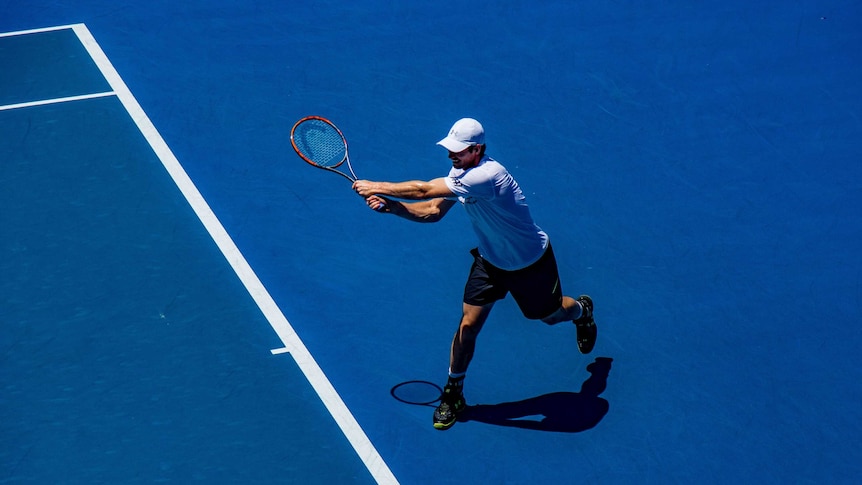 A man hits a backhand shot on the tennis court