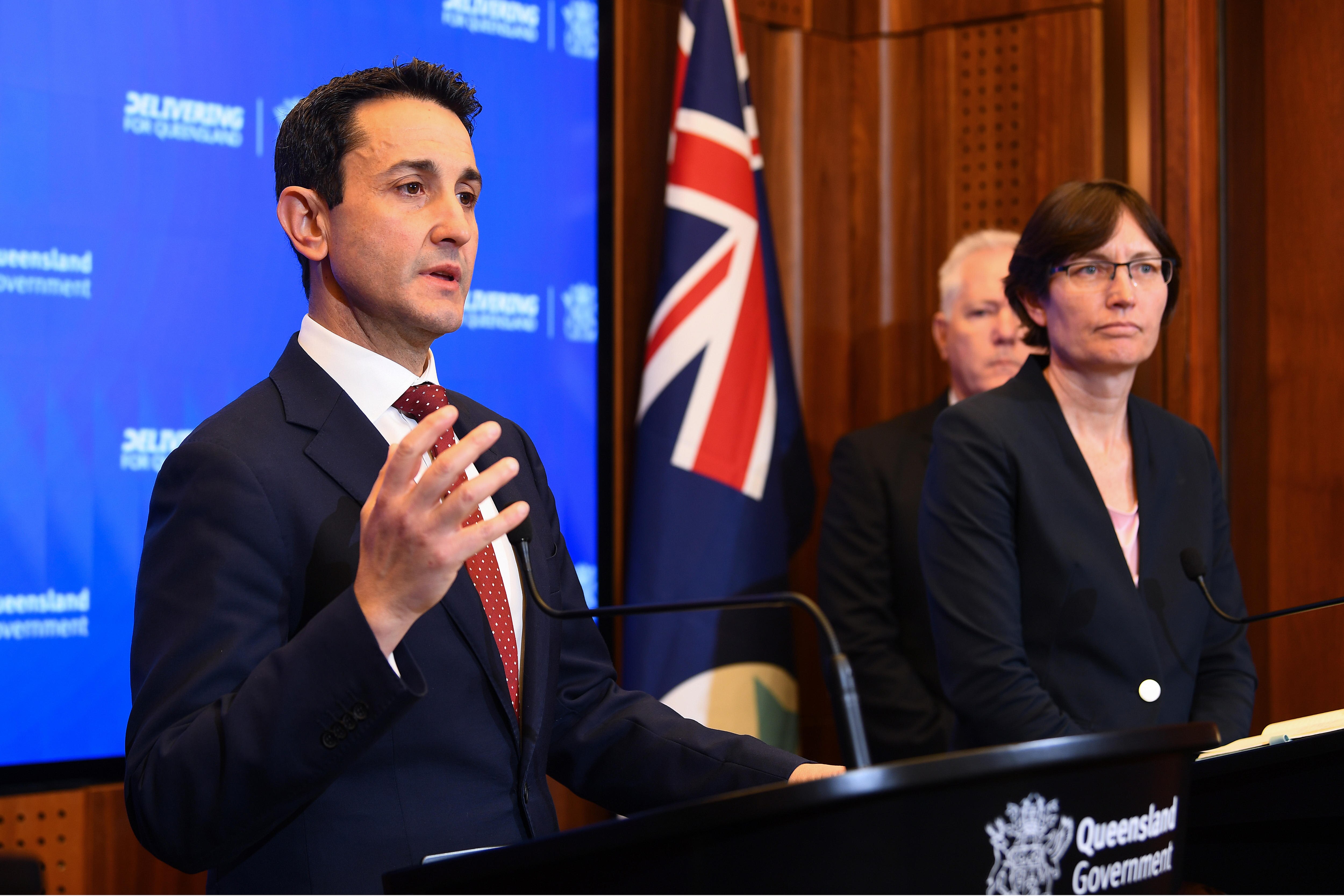 A man in a suit and tie holds his hand up expressively as he speaks