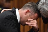 Oscar Pistorius rubs his eyes and is comforted by a woman inside the high court in Pretoria.