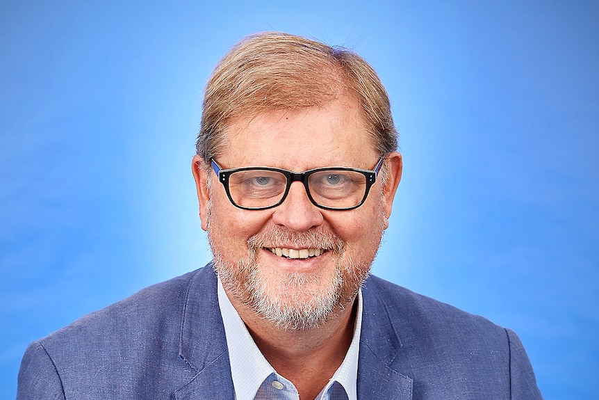 A smiling, bespectacled man with light hair and a salt and pepper beard.