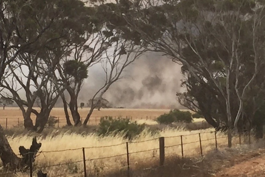 Smoke is visible across a paddock from a bushfire