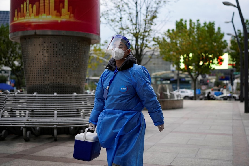 一个穿着蓝色防护服的男人走在街上