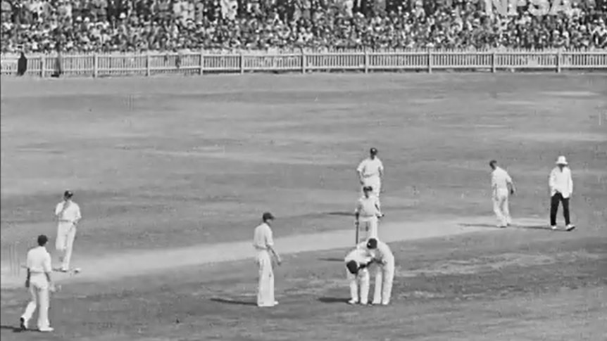 A player can be seen bent over on the cricket pitch.