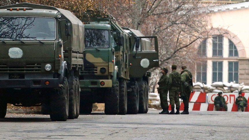 Armed people and military trucks near a checkpoint outside a building in Donetsk.