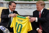 Brazilian president Jair Bolsonaro presents Donald Trump with a gold Brazil number 10 jersey with his name on it.