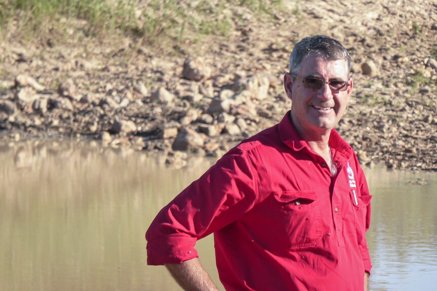 A farmer stands in fornt of a dam