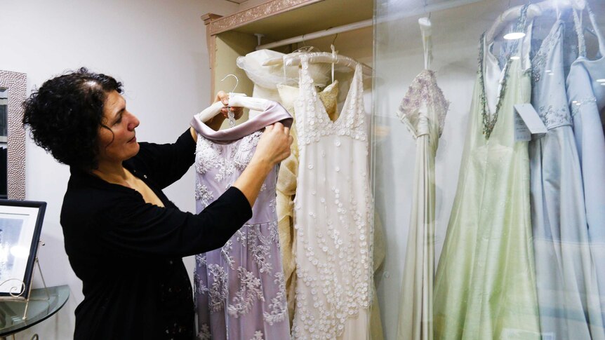 Hajar Gala holding dress in cabinet in her fashion studio