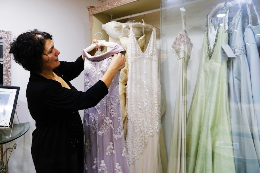 Hajar Gala holding dress in cabinet in her fashion studio
