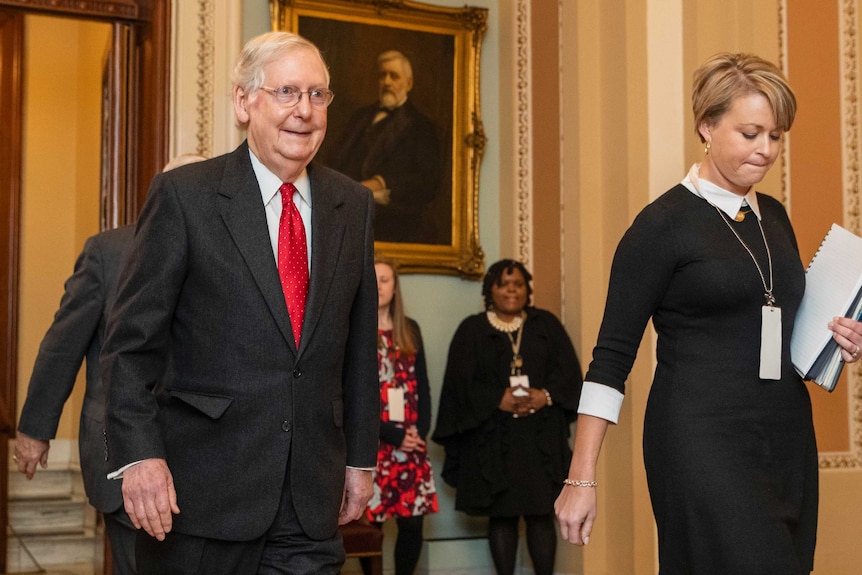 Senate Majority leader Mitch McConnell smiles as he walks along.