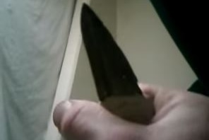 A screenshot from a YouTube video shows a knife held up to the camera and a prisoner in the background.