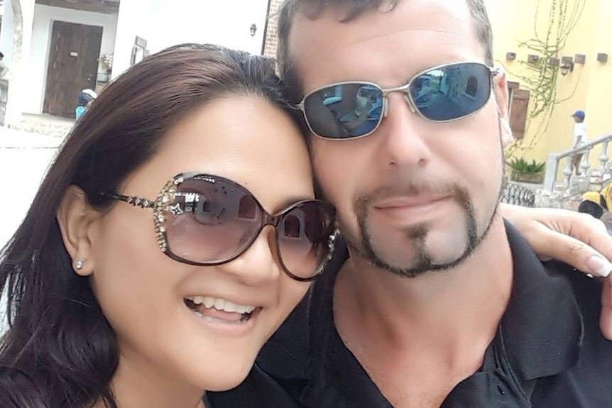 Kanyarat Wechapitak and Luke Joshua Cook pose for a selfie outdoors wearing sunglasses.