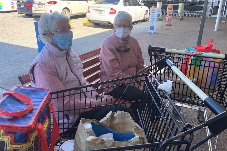 Two elderly women sitting on a bench at a shopping centre