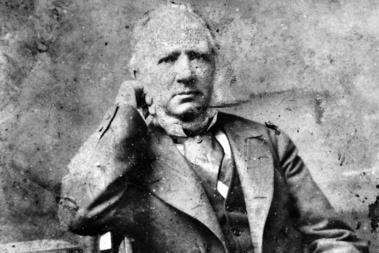 O'Doherty's face and torso seated on a chair with books