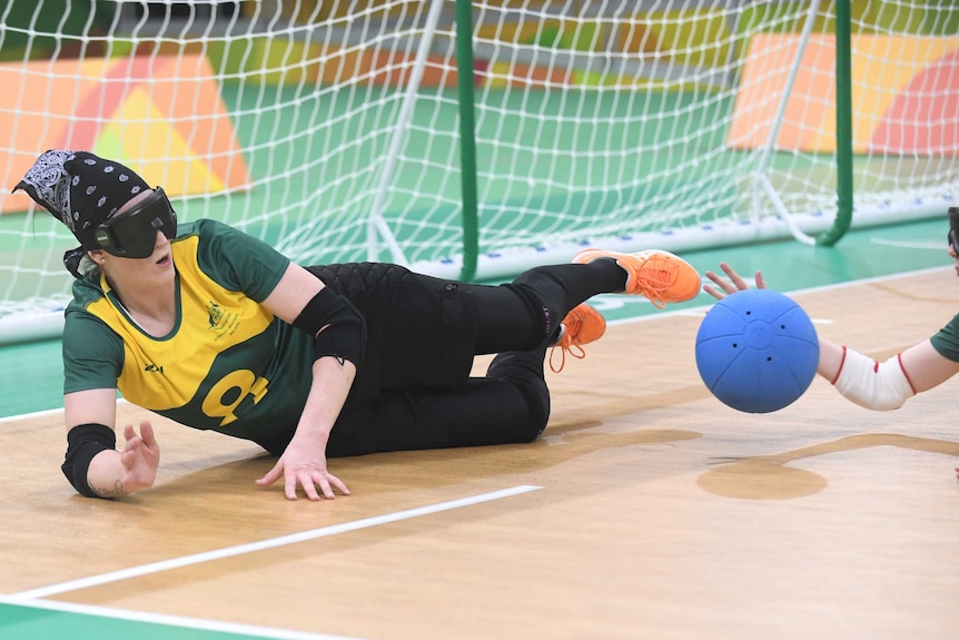 A goalball player slides in front of the goal.