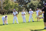 The Warnbro Swans integrated league team stand in a line at catching practice.