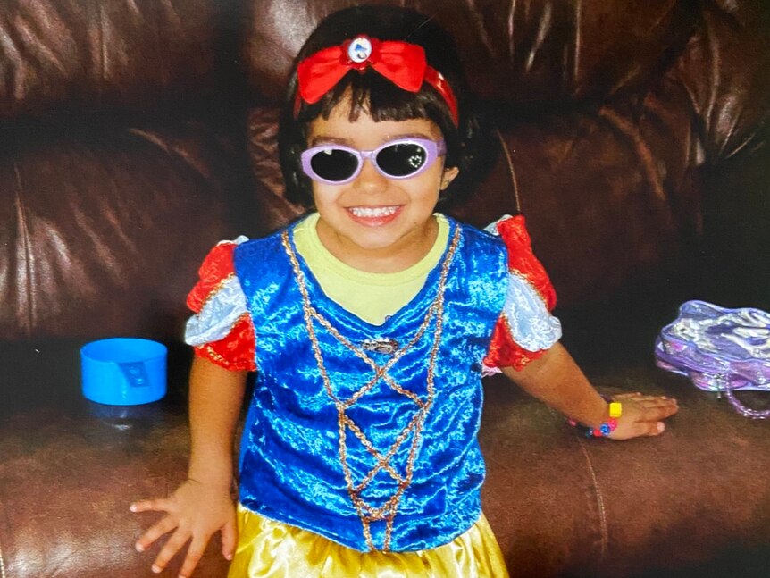 A child in a snow white costume smiling with sunglasses on. 