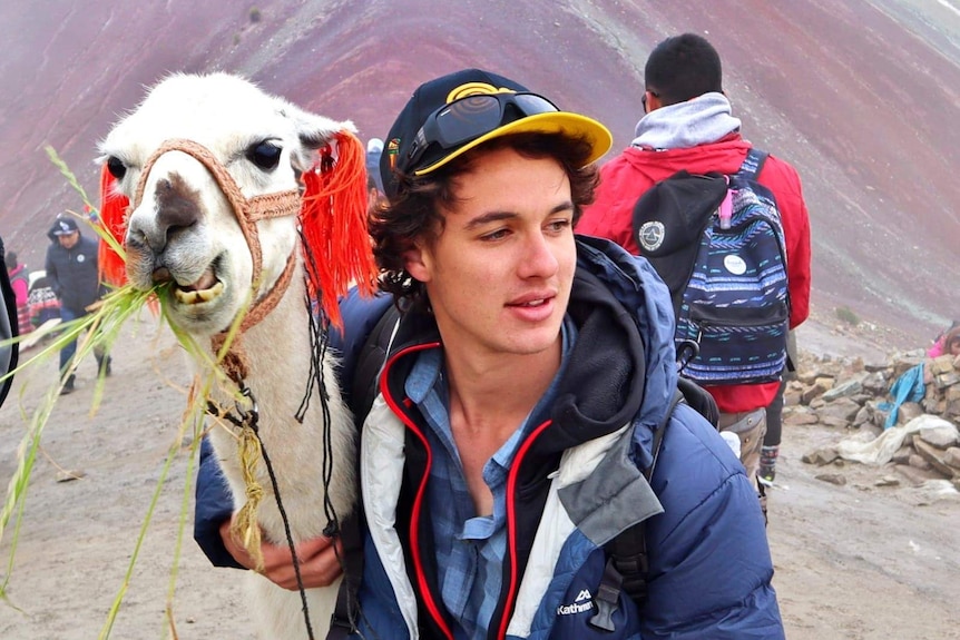 Travis Enright standing next to an alpaca