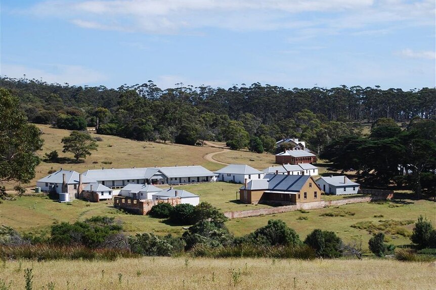 A series of historic buildings on rural land surrounded by bush.