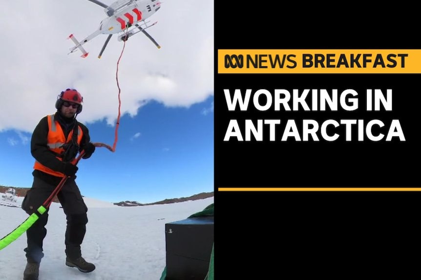 Working in Antarctica: Man at Antarctic station holds rope connected to overhead helicopter