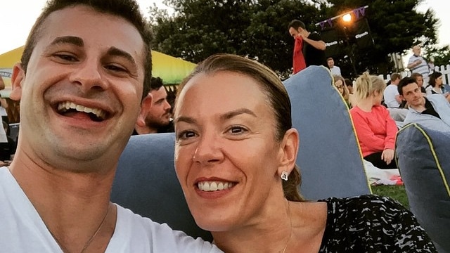 A man and a woman sitting on a bean bag in a park.