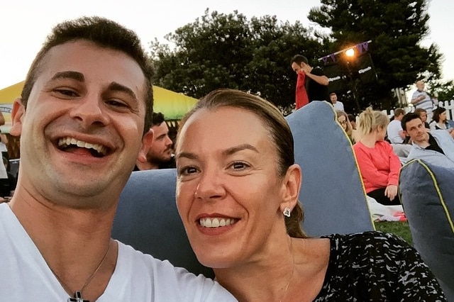 A man and a woman sitting on a bean bag in a park.