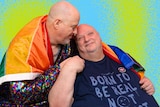 Peter (right) sits with Adrian (right) who plants a kiss on his head while Peter smiles wearing an LGBTQIA+ flag.