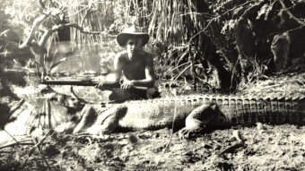 A young shooter kneels next to a dead crocodile in the NT.